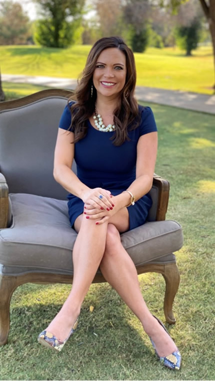 Photo of Kristi Andrews sitting on an upholstered chair on the grass